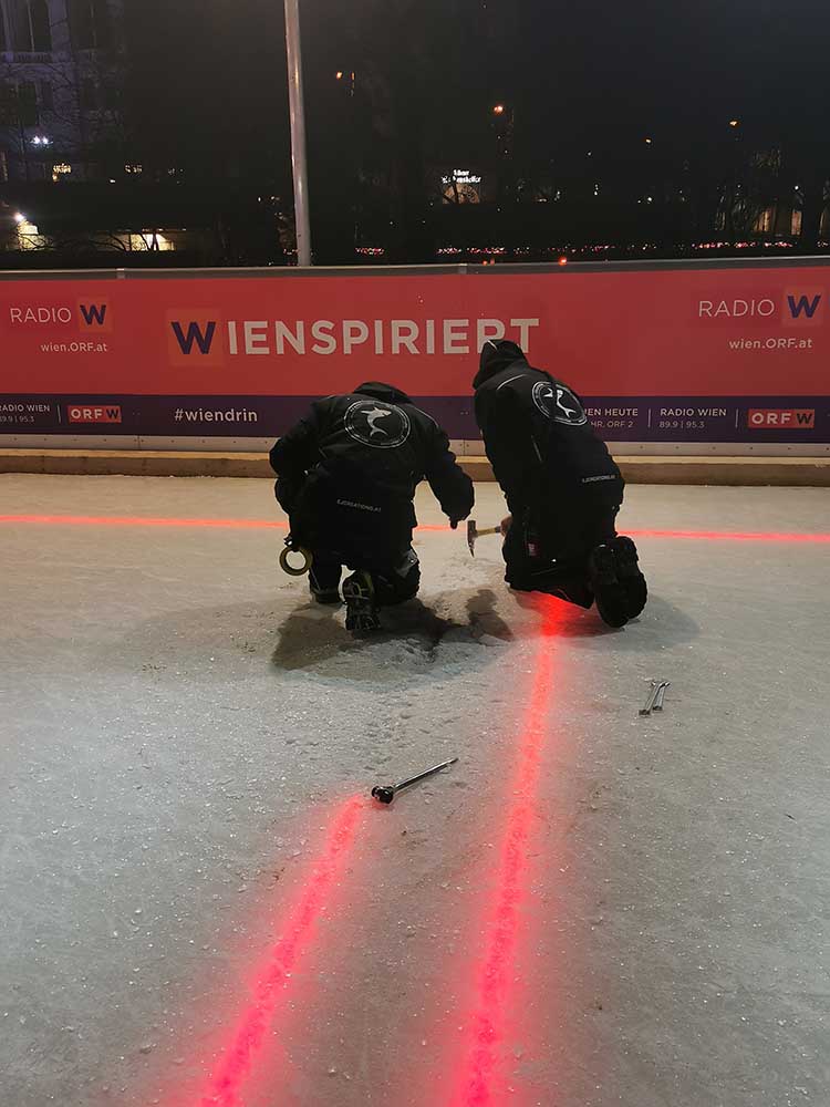Eishockeyfeld mit Technikern – Zwei Techniker arbeiten an LED-Linien auf Eisfläche beim „Wien inspiriert“-Event.