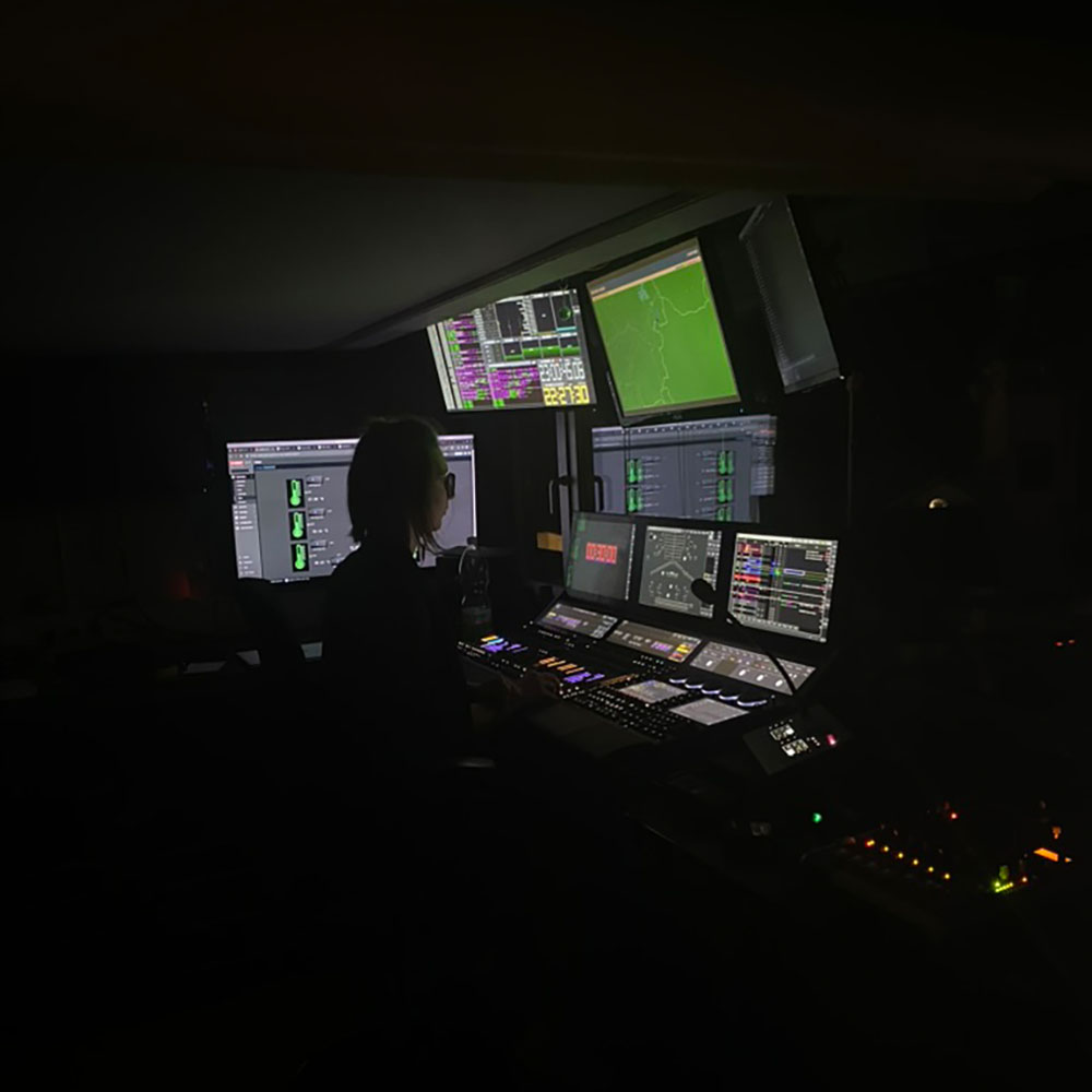 Regiearbeitsplatz – Technischer Regieplatz mit Monitoren und Steuerpult im Dunkeln.